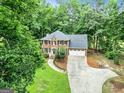 Aerial view of a brick two-story home with a driveway, garage, and surrounded by mature trees at 135 Crimson Rdg, Tyrone, GA 30290