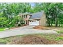 Exterior view of a brick and tan two-story home with a driveway, garage, and surrounded by lush trees at 135 Crimson Rdg, Tyrone, GA 30290