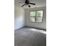 A well-lit bedroom featuring a ceiling fan, carpet flooring and a window that provides ample natural light at 121 Fountain Oak, Villa Rica, GA 30180
