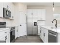 Modern kitchen with stainless steel appliances, white cabinets, quartz countertops, and hardwood floors at 552 Cantrell Drive, Dallas, GA 30157