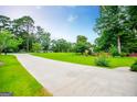 Long concrete driveway with lush green lawn and trees along the side at 65 Pine Haven Ct, Carrollton, GA 30116