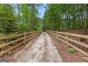 Scenic driveway leading to the property, framed by a wooden fence and surrounded by a beautiful forest at 8129 S Giles Rd, Douglasville, GA 30135