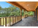 Spacious covered porch with wood ceiling and railing, offering views of the lush surrounding landscape at 8129 S Giles Rd, Douglasville, GA 30135