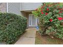 Inviting entryway with a well-manicured hedge and vibrant red roses leading to a white, decorative front door at 7813 Newbury Dr, Jonesboro, GA 30236
