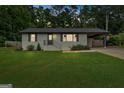Charming, renovated brick ranch on a lush lot with a carport at dusk, offering curb appeal at 30 Mary Ella Dr, Carrollton, GA 30116
