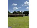 Spacious backyard with lush green grass, mature trees, and glimpses of neighboring houses at 410 Clubland Se Cir, Conyers, GA 30094
