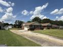 Single-story brick house with a two-car garage and a long driveway under a cloudy blue sky at 410 Clubland Se Cir, Conyers, GA 30094