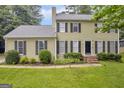 Traditional two-story home with lush landscaping and a classic black front door and shuttered windows at 557 Spring Creek Ne Way, Marietta, GA 30068
