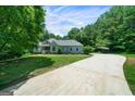 Long concrete driveway leading to a well-maintained home on a lush, green lot with a covered parking structure at 1460 Bakers Bridge Rd, Douglasville, GA 30134