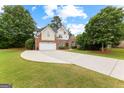 Two-story home featuring manicured lawn, a curved driveway, and lush landscaping at 1602 Cascade Overlook, Peachtree City, GA 30269