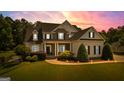 Beautiful home with illuminated landscaping at dusk, showcasing stone accents and a covered front porch at 55 Jolie Ln, Sharpsburg, GA 30277