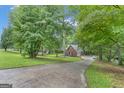 A charming single-story brick home viewed from a long driveway amidst lush green trees and foliage at 190 Willow Lake Ln, Sharpsburg, GA 30277