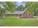 Lovely brick home with manicured lawn and black shutters nestled among mature trees on a partially cloudy day at 190 Willow Lake Ln, Sharpsburg, GA 30277