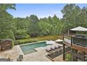 Backyard pool featuring a lounging area with umbrellas and manicured lawn surrounded by trees at 2975 Hickory Hill Rd, Brooks, GA 30205