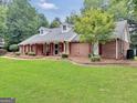 Beautiful brick home showcasing a lush green lawn, mature trees, and classic architectural details at 602 Pine Knoll Court, Mcdonough, GA 30252