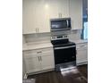 Kitchen with white cabinets and countertops, featuring stainless steel microwave and stove at 5425 Herndon Blvd, Morrow, GA 30260