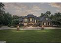 Elegant brick home at dusk, beautifully lit with manicured lawn and mature trees surrounding the property at 1385 Gordon Rd, Moreland, GA 30259
