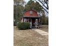Red barn style home with a covered porch, shrubbery, and a sidewalk at 10142 Washington Street, Covington, GA 30014