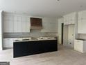 Spacious kitchen with white cabinets, a dark kitchen island, and a wooden range hood at 1291 E M Croy Rd, Sugar Hill, GA 30518