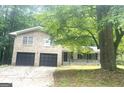 Brick home featuring a two-car garage and a welcoming covered porch, framed by mature trees at 345 Fond Du Lac Dr, Stone Mountain, GA 30088