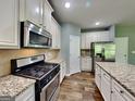 Modern kitchen with stainless steel appliances, granite countertops, and white cabinetry at 3507 Hideaway Ln, Loganville, GA 30052
