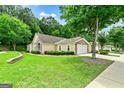 Exterior home view with beautiful lawn, mature trees, stone accents, and attached two-car garage at 140 Rehobeth Way, Fayetteville, GA 30214