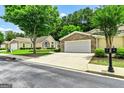 View of home showcasing the two-car garage, manicured lawn, and mature trees in a neighborhood setting at 140 Rehobeth Way, Fayetteville, GA 30214