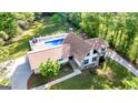 Aerial view of a home with stone and siding, a pool with fence, landscaping, and mature trees at 3222 Bay View Dr, Jonesboro, GA 30236
