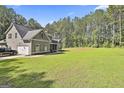 Expansive lawn and a home with an attached garage, surrounded by mature trees at 211 Beavers Rd, Grantville, GA 30220