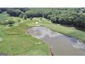 Expansive golf course aerial view featuring a pond with a sandy beach and vibrant green fairways and natural landscape at 103 Golf Terrace Dr, Stockbridge, GA 30281