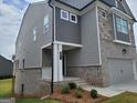 View of the front of a gray home highlighting the brick foundation and covered entryway at 38 Avian Way # 126B, Auburn, GA 30011