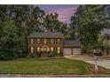 Brick home at dusk featuring a manicured lawn, symmetrical design, and a two-car garage at 1911 Geyser Trce, Lawrenceville, GA 30044