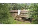 Backyard view featuring a brick home with a wooden deck and stairs to a concrete slab at 115 Club Cir, Stockbridge, GA 30281