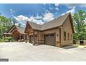 Side view of three-car garage with stone accents, and professionally landscaped yard at 177 Selfridge Rd, Mcdonough, GA 30252