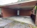 Large covered carport featuring brick columns, wood siding, and entrance to the home at 1932 Pharrs Rd, Snellville, GA 30078