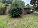 Ranch home featuring a covered carport, brick exterior, mature trees and an overgrown front yard at 1932 Pharrs Rd, Snellville, GA 30078