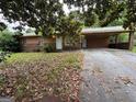 Ranch home featuring a covered carport, front yard with mature trees and a long driveway at 1932 Pharrs Rd, Snellville, GA 30078