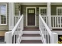 Inviting front porch with white railings and a stylish front door that has beautiful trim at 90 Thomas Overby Dr, Sharpsburg, GA 30277