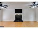Bright living room featuring a stone fireplace, hardwood floors, and ceiling fans at 90 Thomas Overby Dr, Sharpsburg, GA 30277
