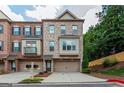 Charming brick townhome featuring a two-car garage, multiple windows, and well-manicured landscaping at 275 Autry Mill Ln, Suwanee, GA 30024