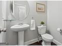 Elegant half bathroom features a pedestal sink, a round mirror, and modern fixtures at 733 Wexford Cove Way, Mableton, GA 30126