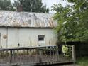 This is the rear exterior featuring a large deck area, peeling paint, and a damaged roof at 11591 Turner Rd, Hampton, GA 30228