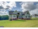 Charming home with a covered entry, light green siding, stone accents, and a sprawling lawn at 3076 East Lake Rd, Mcdonough, GA 30252
