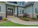 Inviting front entry with stone-covered columns, a stone walkway, and beautifully landscaped flowerbeds at 3076 East Lake Rd, Mcdonough, GA 30252