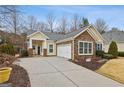 Inviting home with a two-car garage, yellow siding, rock accents, and a manicured lawn at 6775 Marlow Dr, Cumming, GA 30041