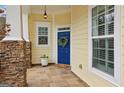 Charming covered front porch with stone columns, a blue door, and tiled flooring at 6775 Marlow Dr, Cumming, GA 30041