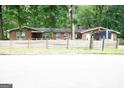 Street view of single-story brick home with mature trees and rustic fence at 3010 Waters Sw Rd, Atlanta, GA 30354