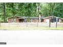 Single-story brick home with lush, mature trees and rustic wooden fence at 3010 Waters Sw Rd, Atlanta, GA 30354