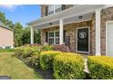 Inviting front porch with stone accents, lush landscaping, and a welcoming front door at 140 Canyons, Hampton, GA 30228