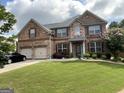 Inviting two-story brick home with lush lawn, landscaped yard, and two-car garage at 1141 Norsworthy Ml, Hampton, GA 30228